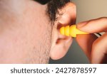 Small photo of On World Hearing Day, man wears earplugs to protect hearing and get rid of oppressive noise. World Hearing Day campaign concept