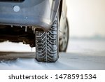 Close up of a car tire parked on snowy road on winter day. Transportation and safety concept.