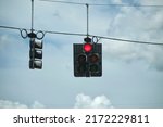 Bright red stop traffic lights high above street on blue sky background