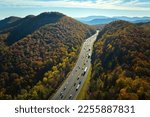 View from above of I-40 freeway in North Carolina heading to Asheville through Appalachian mountains in golden fall season with fast driving trucks and cars. Interstate transportation concept