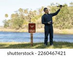 Operator is preparing to fly his quadcopter in national park no drone area. Man unlawfully using his UAV near restriction notice sign