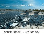 Small photo of Top view of destroyed by hurricane Ian photovoltaic solar panels mounted on industrial building roof for producing green ecological electricity. Consequences of natural disaster in Florida