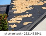 Small photo of Ruined rooftop in need of repair. Wind damaged house roof with missing asphalt shingles after hurricane Ian in Florida
