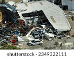Small photo of Automotive workshop destroyed by hurricane wind with damaged cars under ruins in Florida. Consequence of natural disaster