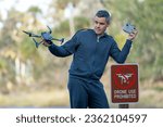 Drone operator is disappointed because he isn't allowed to fly his quadcopter in national park no drone area. Man is unable to use his UAV near restriction notice sign. Airspace use regulations