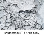 Cracked concrete texture background. Grey surface with cracks close up. A lot of pieces of splintered plaster. Abstract concept of split, dissent, disagreement, discord. Sunny day with shadows.