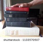 Small photo of A hand on top of a stack of bibles is ready to swear the truth