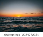 Small photo of As the sun dips below the horizon, a sense of tranquility blankets the scene. Shades of coral and tangerine meld with the tranquil blues of the ocean's depths, creating a transition from day to night