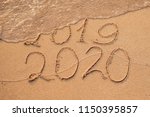 New Year 2020 is coming concept - inscription 2019 and 2020 a beach sand, the wave is almost covering the digits 2019
