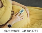 Small photo of Pregnant woman with pulse oximeter on finger. Doctor measuring oxygen saturation level while visiting expectant mother with coronavirus disease at home, cropped. Pregnancy and covid-19 concept