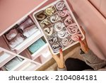Small photo of Closeup caring mother hands neatly folded female kids socks in plastic case box Marie Kondo method. Female during spring cleanup tidying up cupboard with childish clothes minimalist space organize