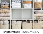 Small photo of Bed linens closet neatly arrangement on shelves with copy space domestic textile Nordic minimalism comfortable storage. Rolled towels in straw basket duvet cover sheet pillow plaid in cupboard