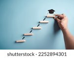 Small photo of Steps of education leading to success goal. Taking strategic steps towards graduation. Career path and first for business, Graduation achievement goals concept. Graduation cap on wooden block.