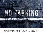 No parking text written and white line with broken cement wall, No parking sign word on street.