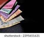 Small photo of Rupiah money in Wallet with Black background. IDR 100.000 IDR 20.000 IDR 10.000 IDR 5000 Rp2000