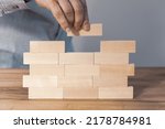 Small photo of Creating a stable foundation for the company's operations, Business development based on solid foundations Creative concept, Entrepreneur builds a wall of wooden blocks, Building customer trust