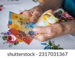 Small photo of pensioner holds a bunch of low denomination banknotes in her hands, Cost of living for a senior citizen in Switzerland, Pensions and the Swiss social system for the elderly, financial concept