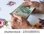 Small photo of An old woman holds 100 Polish zloty banknotes in her hands, Polish money, Concept, Pension, allowance, help for the elderly