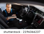 Car mechanic repair service and checking car engine by diagnostics software on tablet computer. Expertise mechanic working in automobile repair garage.