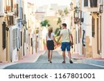 Young happy couple walking holding each others hand in Spanish town Denia. Stylish man and woman on vacations in Spain, Europe. Tourism and travelling concept.