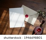Envelope back side with red wax seal and blank card invitation Mockup. Top view on wooden background. with clipping path