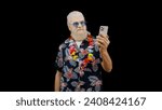 Small photo of Happy oldster in a Hawaiian shirt takes a selfie with his smartphone, enjoying his vacation