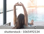Small photo of Good life of easy relax Asia woman do nothing or daydreaming with hand stretching up sitting at home or hotel near swimming home. Happy people lifestyle concept.