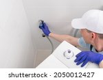 the master in protective gloves, installs the washing machine, connects it to the water supply and drainage systems