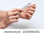 Small photo of the girl saws with a nail file and shaped her nails during the nail extension procedure in a beauty salon. Professional hand care.