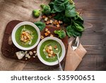 Green cream soup of spinach and broccoli. with the addition of parmesan and blue cheese with croutons. a wooden background. conception healthy food and diet.