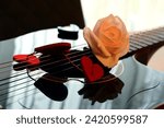 Small photo of Pink rose and red hearts on the soundboard of a dark guitar.