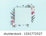 Easter composition. Easter eggs, flowers, paper blank on pastel blue background. Flat lay, top view, copy space.