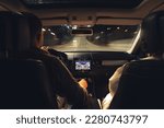 A man and a woman are driving in a car at night, the view from the car to the road.
