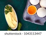Small photo of Homemade sauce Mayonnaise and ingredients eggs, oil, lemon, mustar on green background. Top view