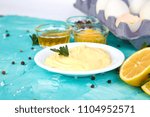 Small photo of Homemade sauce Mayonnaise and ingredients eggs, oil, lemon, mustar on blue background. Top view
