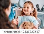 At the doctor's appointment. A candid emotional photo of a child sitting in a dental chair, holding a toy rabbit and cheerfully giving a high-five to the nurse.