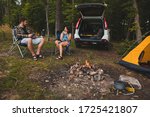 couple sitting in portable chairs drinking tea talking. camping summer activities
