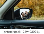 smiling man in the side mirror of the car in the autumn season
