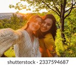 two pretty women take a selfie at sunset