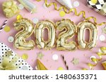 2020, Happy New Year! Golden balloon numbers, shiny streamers, confetti and  wrapped  gift boxes on pastel pink background. Happy 2020 Year. Top view.