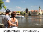 Man and woman siting on quay near river Vltava with beautiful Charles bridge view in sunny day.