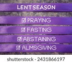 Small photo of Christianity concept about Ash Wednesday, Good Friday, Lent Season and Holy Week. LENT SEASON, PRAYING, FASTING, ABSTAINING and ALMSGIVING written on purple ribbons. With blurred background.