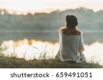 A girl sitting on the river bank in silence