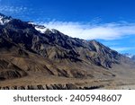Small photo of Towering mountains, adorned with a dusting of snow on their summits, dominate the landscape. The distinctive yellowish-brown hue of the rocky terrain