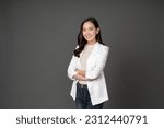 Small photo of Asian female executive with long hair She smiled brightly and confidently stood with her arms crossed. She wore a white suit. and stand to take pictures with a gray scene in the studio