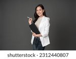Small photo of Asian female executive with long hair Smiling and giving outstanding eyes Working with a tablet and a pen wearing a white suit and stand to take pictures with a gray scene in the studio