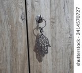 Small photo of Cultural Elegance Unlocked – A Captivating Image of a Khamsa Keychain Adorning the Lock of an Armoire, Blending Wardrobe Security with Spiritual Aesthetics in Intricate Detailing and Middle Eastern