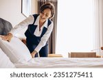 Small photo of Woman housekeeper preparing bed cloths and pillows in the hotel room
