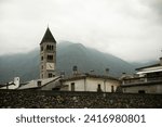 Small photo of Timeless charm: Old buildings with a vintage clock tower, set against a misty mountain backdrop. A captivating scene marrying history and nature's mystique.