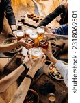 Small photo of Friends cheering beer glasses on wooden table covered with delicious food - Top view of people having dinner party at bar restaurant - Food and beverage lifestyle concept